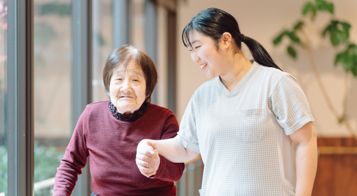手を繋いで歩く高齢者とスタッフ